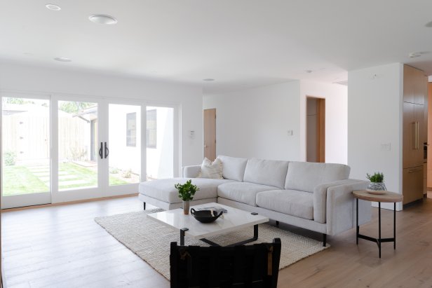 A white-walled living room with large white sectional sofa