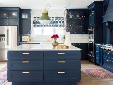 Blue and white kitchen features antique area rugs and green pendant.