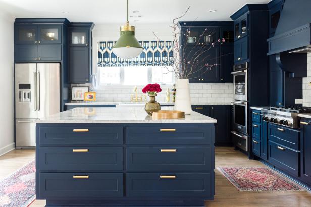 Blue and white kitchen features antique area rugs and green pendant.