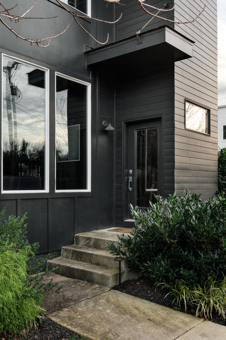 If you're considering painting your own home's exterior black, never underestimate the power of each surface. To minimize the appearance of the simple trim, fascia and doors, Chad painted them all the same shade of black as the siding, but then brought attention to the oversized architectural windows with a touch of white for high contrast. 