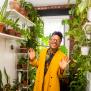 Person in yellow coat poses for camera surrounded by indoor plants