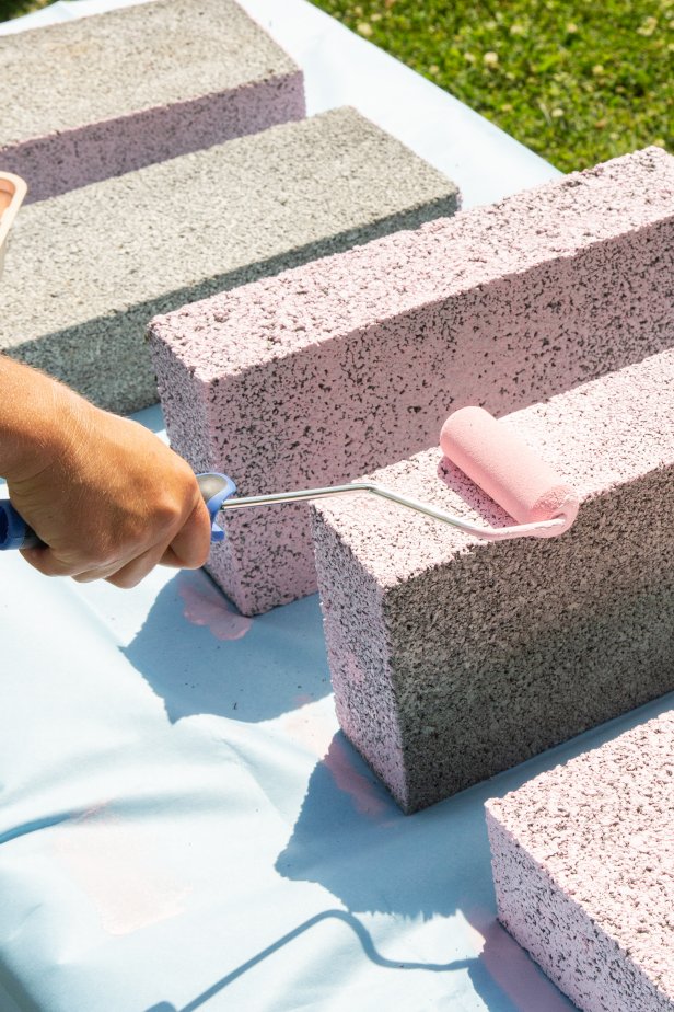 Paint standard cinderblocks a colorful pink using a roller. Then adhere them together with caulking to create a stylish, step entry point to the pool.