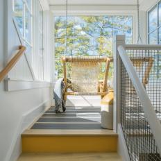 Enclosed Contemporary Porch Landing With White Windows and Pale Wood Bench Swing
