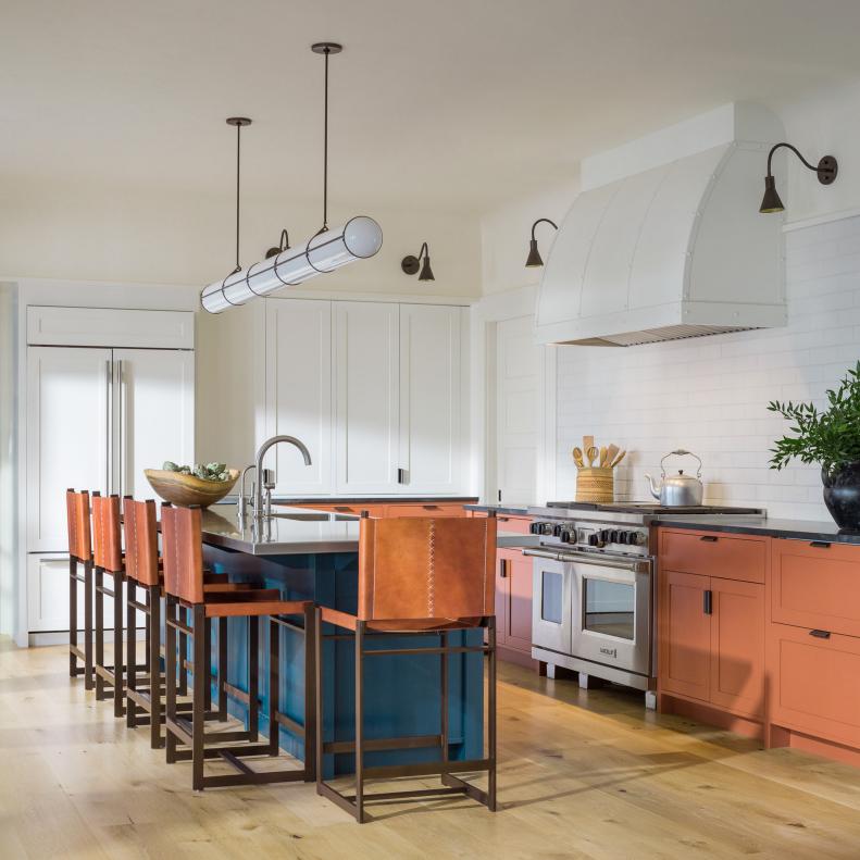 White kitchen with orange cabinetry and seats, and teal island. 