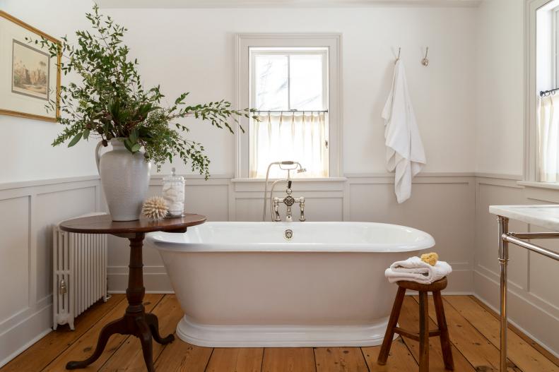 White bathroom with soaker tub and antique wood floors.