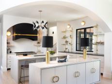 Gold Accents on Range Hood, Sconces in Kitchen With Two Marble Islands