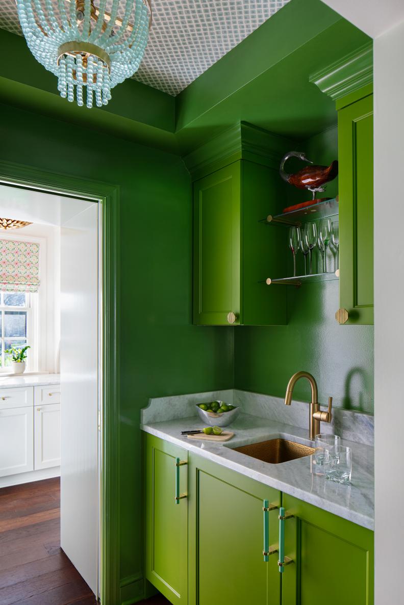 Bright green home bar with lacquered paint and wallpapered ceiling. 