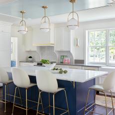 Crisp White Kitchen With a Blue Island and Large Windows Looking Into the Garden