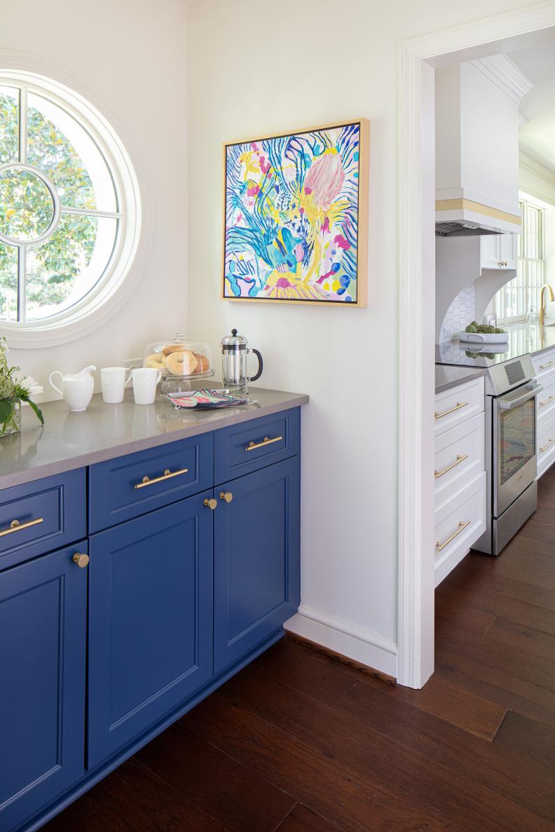 Coffee bar with bold blue cabinetry and bright circular window. 