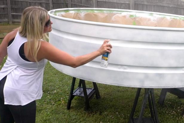 Cover and tape the inside of the pool with leftover craft paper to protect it from overflow spray paint. Next, add two coats of white primer to the outside of the tank. Tip: You will need 10-11 cans of primer white spray paint for an 8’ stock tank. Let the paint dry overnight.
