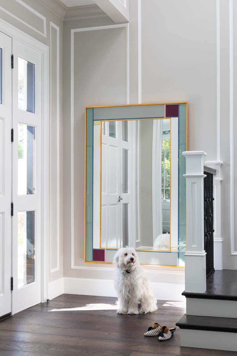 Little Dog Sits in Foyer, Colorful Mirror and Dark Hardwood Staircase