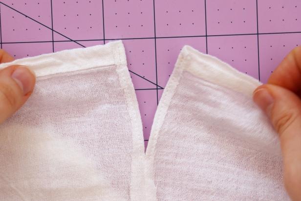 Use your fingers to lay the side seam flat, and then pin the remaining fabric on each side so they line up with the side seam. Sew around this V shape. Repeat on the other side.