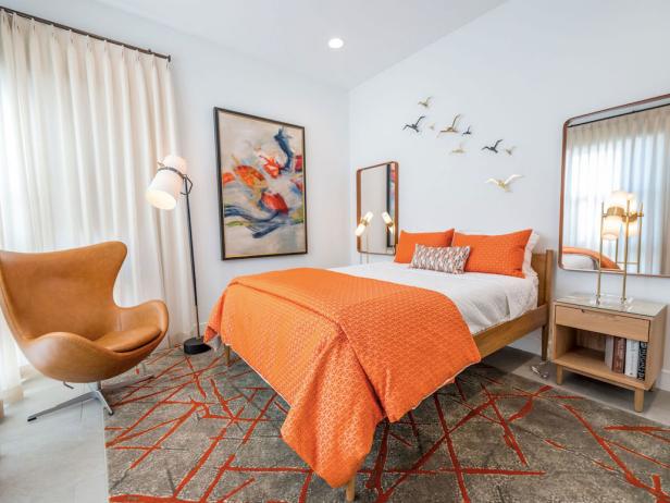 A midcentury modern bedroom with orange accents and an egg chair
