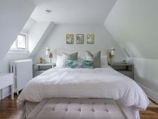 White bed with trio of botanical artwork, grey nightstands and lamps.