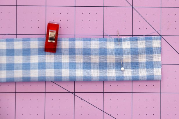 Cut your fabric to 22” x 3.5”. Fold it in half lengthwise with right sides together. Mark 1.5” from each end with a pin, and then pin or clip it together along the entire length.
