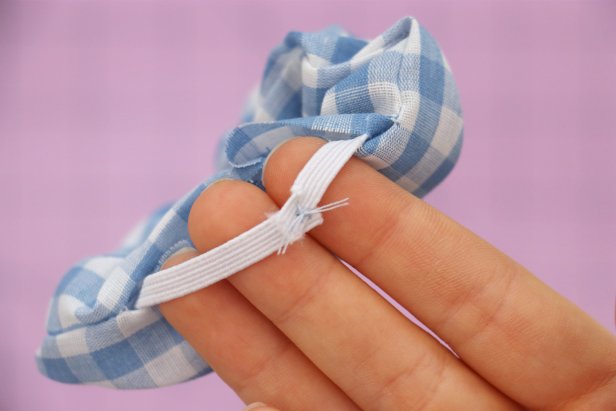 Cut an 8” piece of elastic. Add a safety pin to the end and feed it through the scrunchie. Hand sew the ends of the elastic together. These stitches can be messy and uneven, since it will be hidden inside the scrunchie.