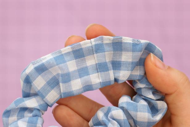 Sew the fabric opening closed by folding in the extra fabric and sewing the edge of the seam. Then adjust the fabric evenly around the elastic to finish your basic scrunchie.