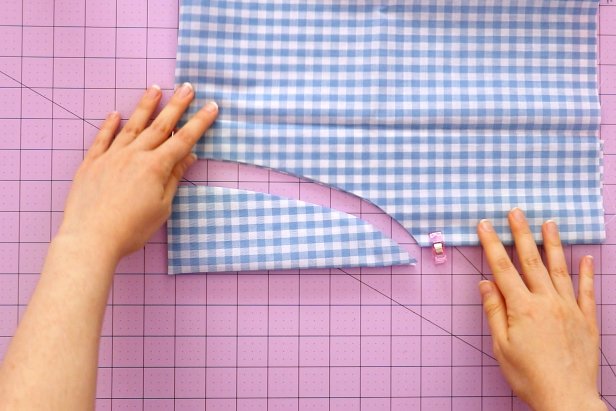 To make the scarf, fold your fabric twice so you have four layers. Cut a long curve between the folded edges. This curved piece should measure around 8” x 1.5.” Unfold it to get a long oval that measures around 16” x 3.” Fold it in half lengthwise with the right sides together and press it with an iron.