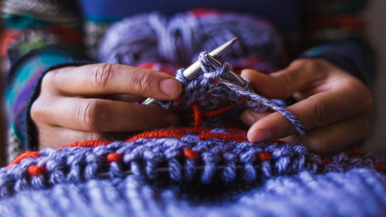 Woman's Hands Form Stitches With Knitting Needles And Yarn