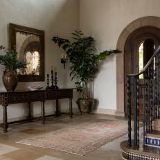 Grand Foyer With Beautiful Mediterranean Tile Stairs and Arched Front Door