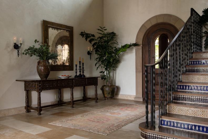 Foyer with a large arched front door and Mediterranean tile stairs. 