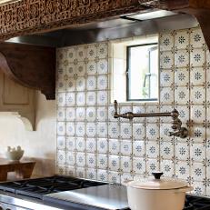 Intricate Wood Carved Range Hood and Mosaic Tile Backsplash