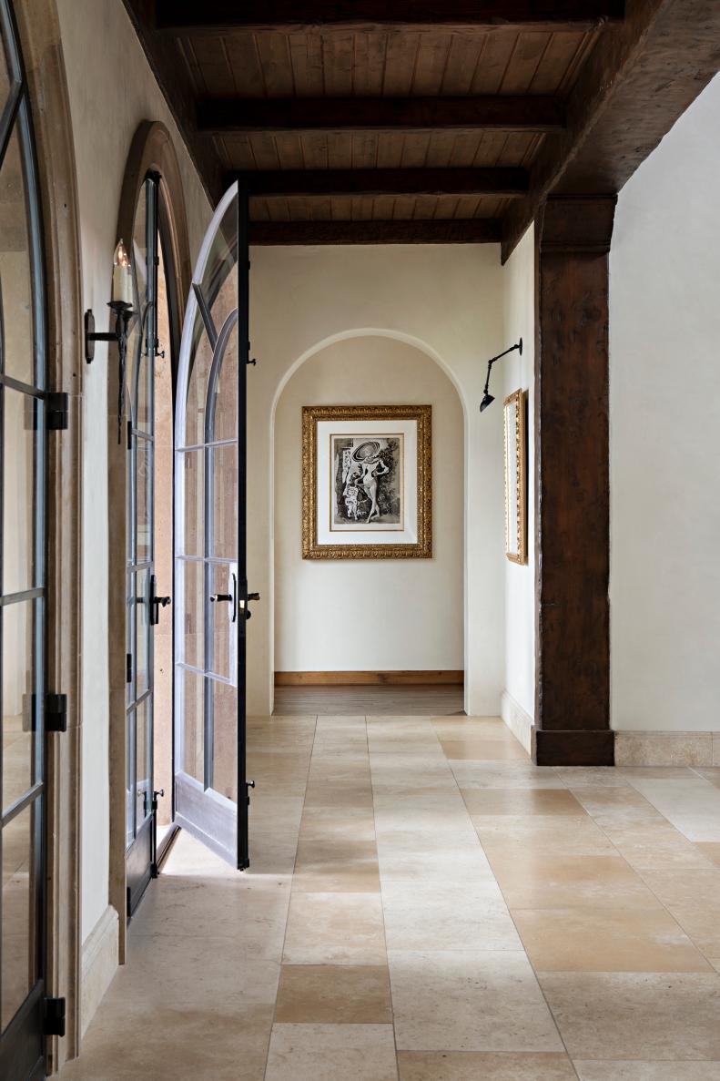 Soft colored hallway with archways and arched double glass doors. 