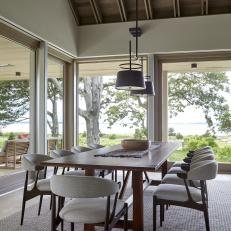 Neutral Contemporary Dining Room With Midcentury Chairs, Exposed Beams and Waterfront Views 
