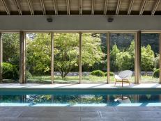 Long rectangular indoor pool with floor to ceiling windows and roof. 