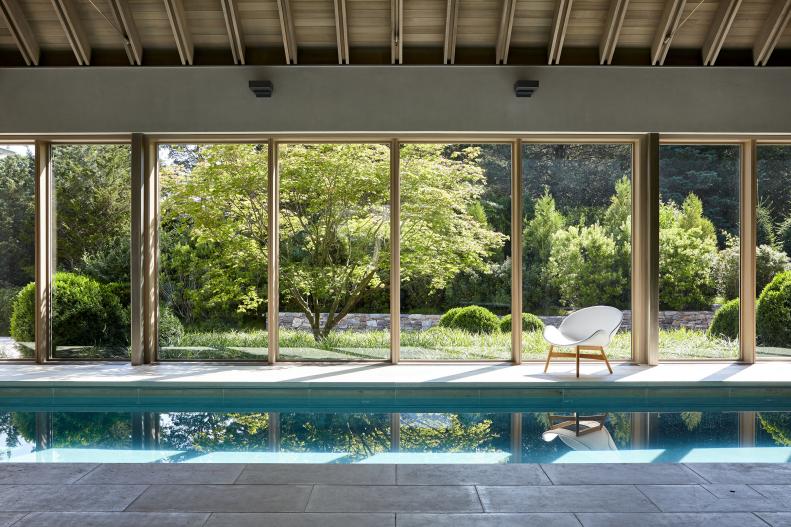 Long rectangular indoor pool with floor to ceiling windows and roof. 