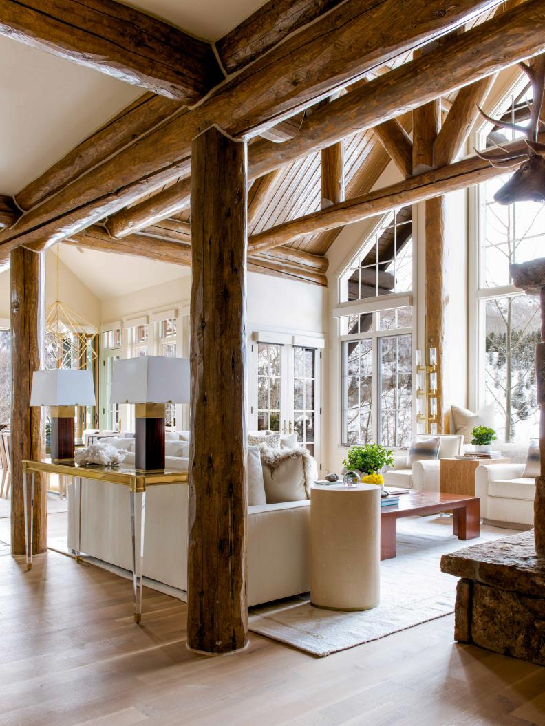 Living room with tree trunk columns and floor to ceiling window. 