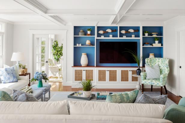 White living room with blue-backed built-in shelving around TV.