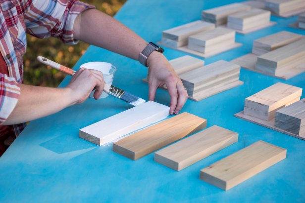 Priming the wood pieces before adding layer of paint. 