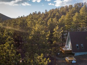 An aerial view of a mountain cabin surrounded by pine trees