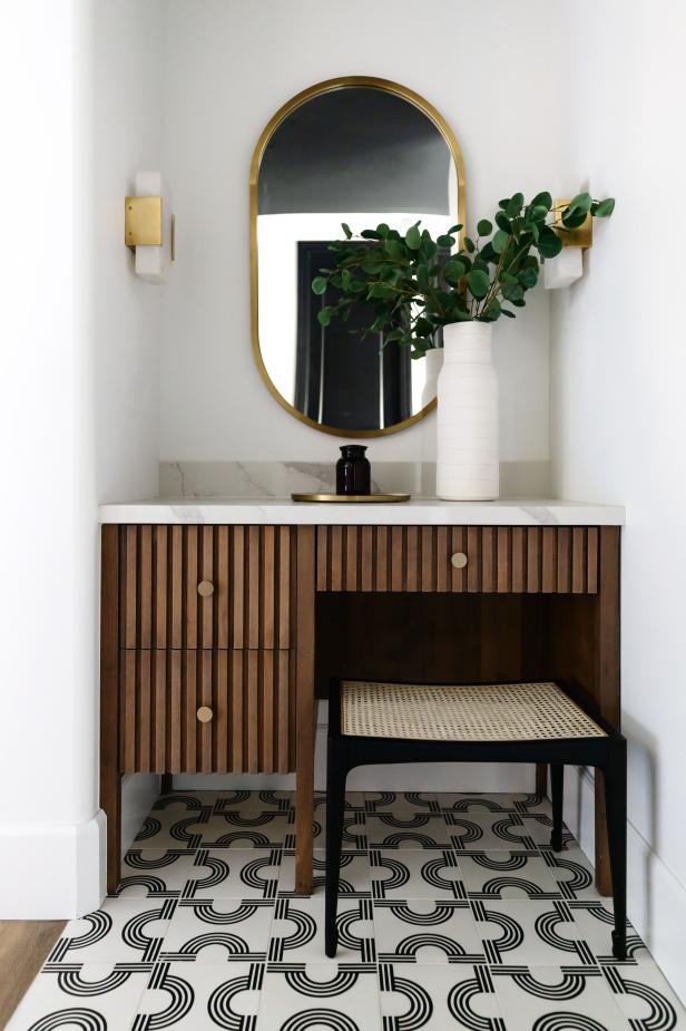 White nook with gold mirror, leafy arrangement and black pot.