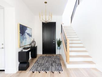 Contemporary Foyer With Black Door, Golden Chandelier, Graphic Rug and Stairs 