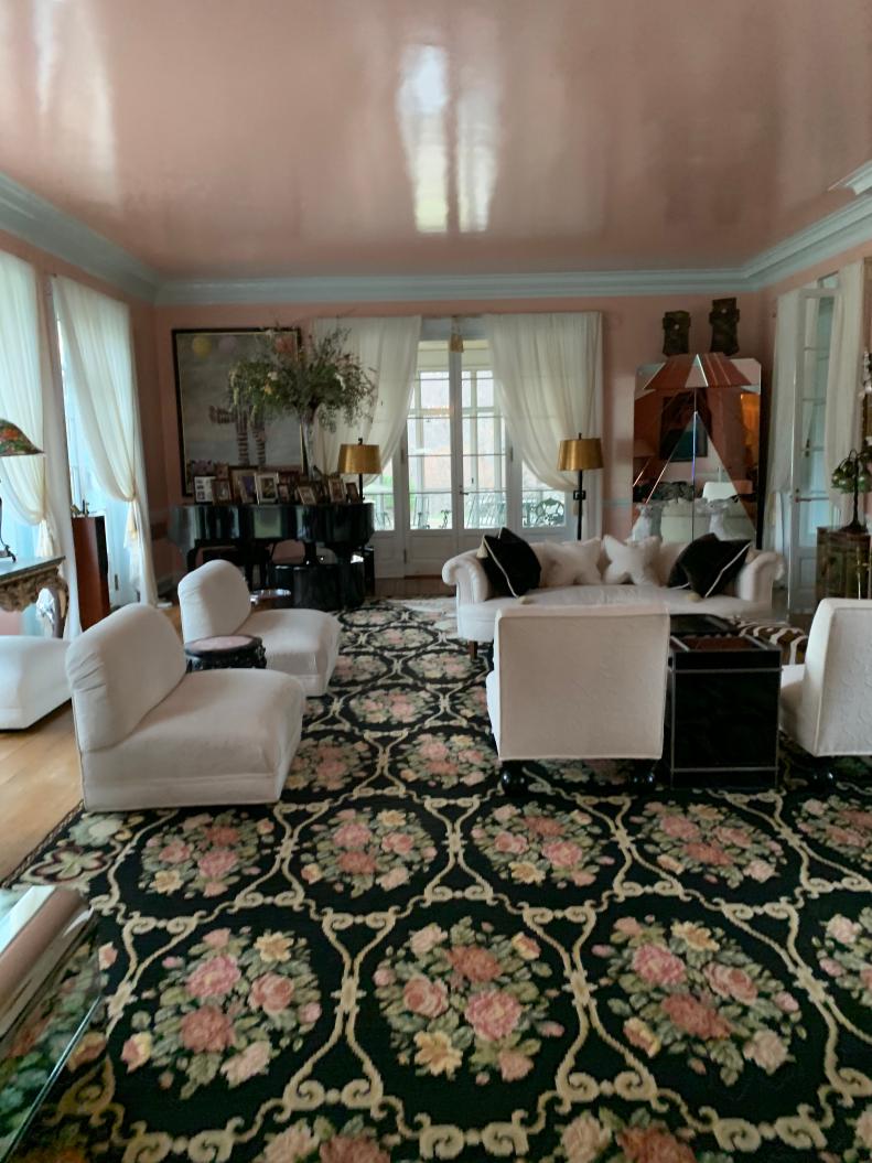 Room with pink ceiling and walls, floral carpet and white furniture.