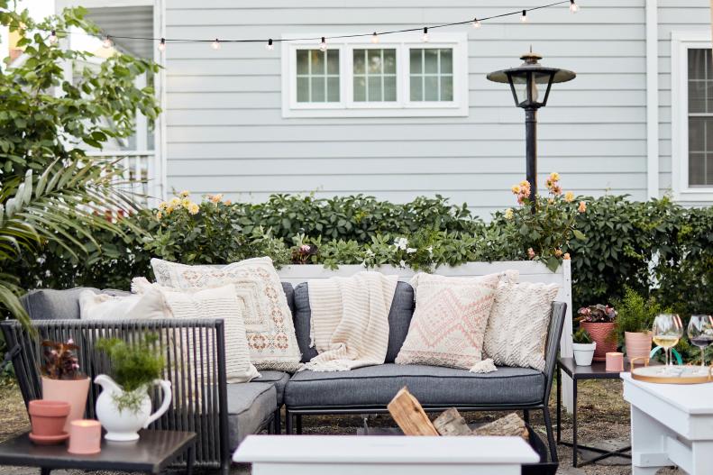 This L-shaped, dark gray outdoor sofa provides seating and frames a corner of the patio area.