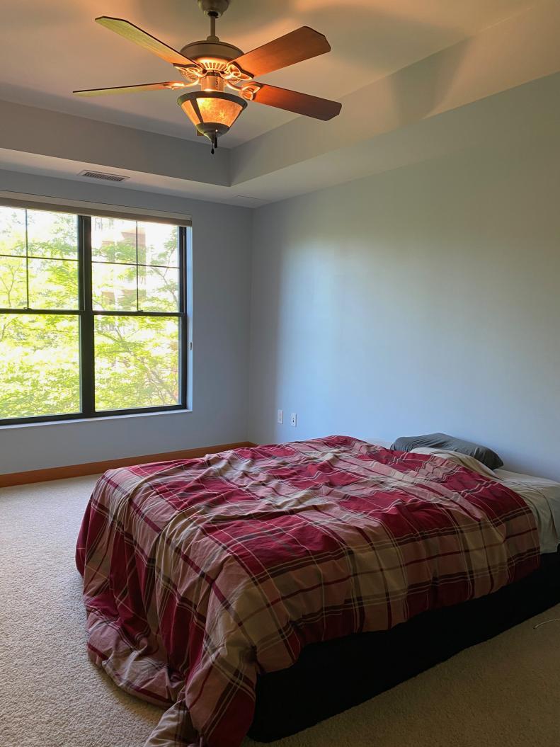 This Dark Bedroom With a Bed and Ceiling Fan Has Little Other Embellishment