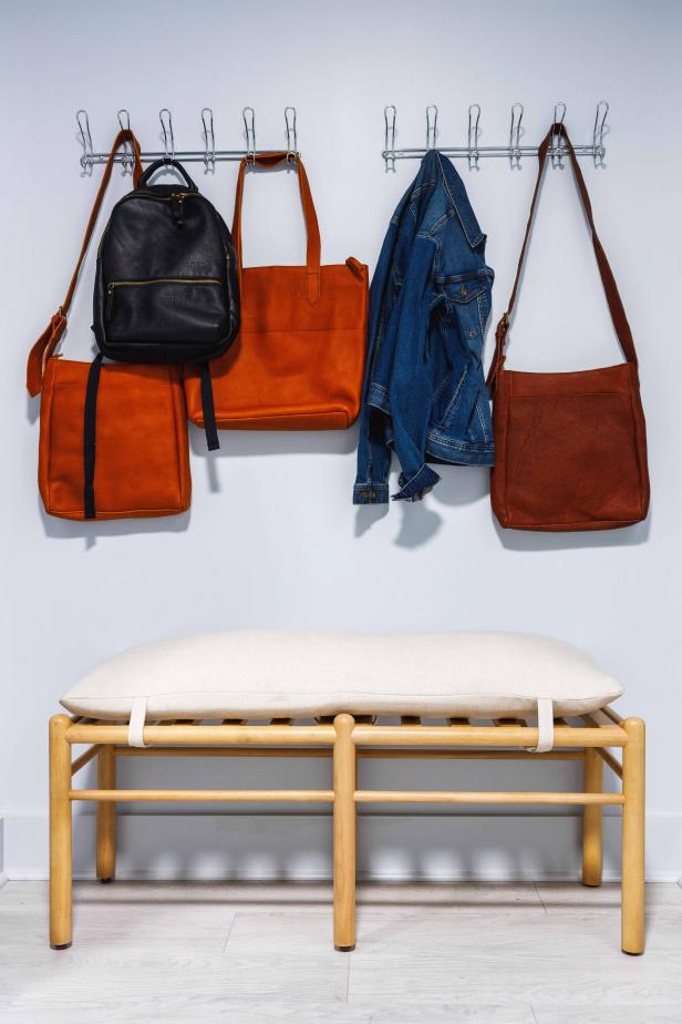 A cushioned wood bench offers seating for taking shoes on and off, with two wall racks above for handbags, jackets, and other frequently used accessories.