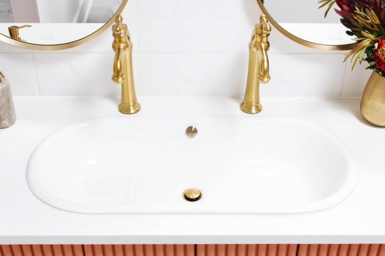 The vanity’s two white elongated capsule sinks have a gently curved, organic shape. The distinctive sinks are made of enameled cast iron, with a smooth enameled interior.