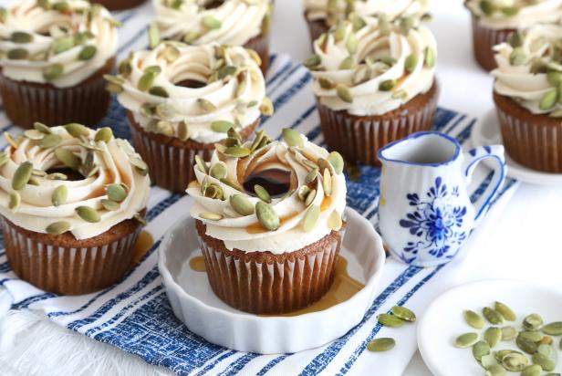 Pumpkin-maple cupcakes topped with maple frosting and pumpkin seeds served in a small ramekin