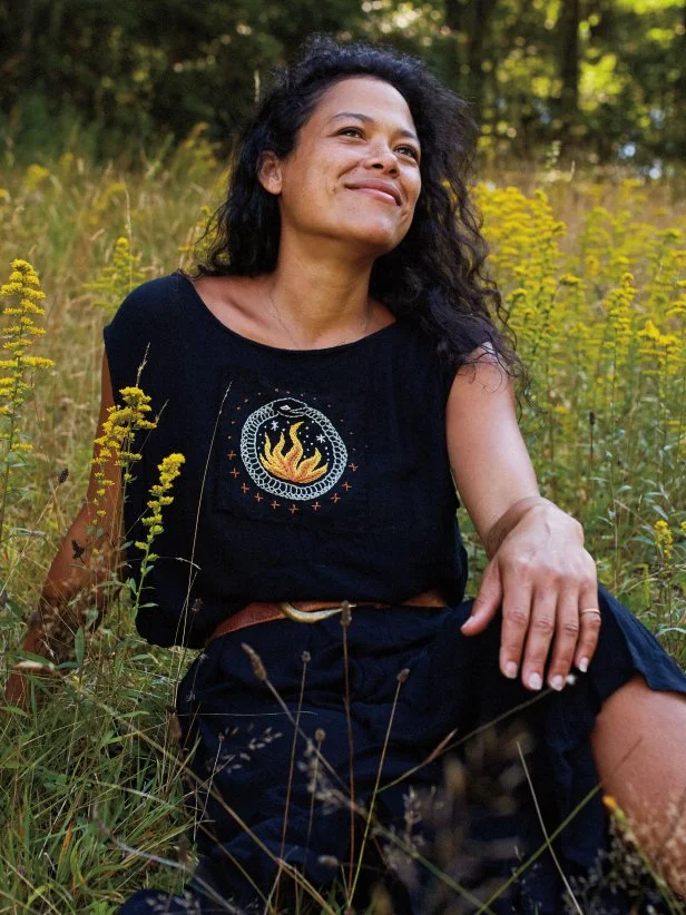 Woman Poses for Camera Wearing Embroidered Clothing in Grassy Field