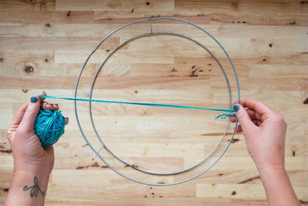 With the larger of the two hoops facing up, tie one end of the twine onto a vertical support. (3-1)Make a knot. Run the twine directly across the hoop to the other side and over the top of the hoop. (3-2)  Loop twine around the edge, back up through the center and over the opposite edge. (3-3) With each pass of the twine, work in a figure eight. Loop twine around each edge, up through the middle, over the center and then under the opposite edge. (3-4) Leave approximately 1/2 inch between each loop. Pause occasionally to adjust your twine and spacing. Keep twine taught, but not tight. Pulling too tight will cause the basket to warp.