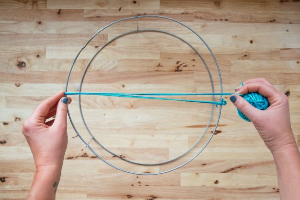 With the larger of the two hoops facing up, tie one end of the twine onto a vertical support. (3-1)Make a knot. Run the twine directly across the hoop to the other side and over the top of the hoop. (3-2)  Loop twine around the edge, back up through the center and over the opposite edge. (3-3) With each pass of the twine, work in a figure eight. Loop twine around each edge, up through the middle, over the center and then under the opposite edge. (3-4) Leave approximately 1/2 inch between each loop. Pause occasionally to adjust your twine and spacing. Keep twine taught, but not tight. Pulling too tight will cause the basket to warp.