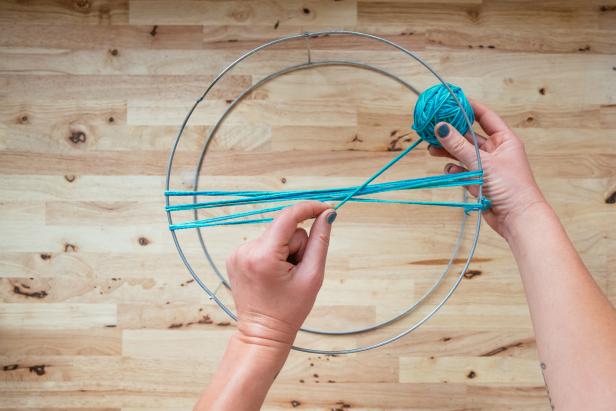 With the larger of the two hoops facing up, tie one end of the twine onto a vertical support. (3-1)Make a knot. Run the twine directly across the hoop to the other side and over the top of the hoop. (3-2)  Loop twine around the edge, back up through the center, and over the opposite edge. (3-3) With each pass of the twine, work in a figure eight. Loop twine around each edge, up through the middle, over the center and then under the opposite edge. (3-4) Leave approximately 1/2 inch between each loop. Pause occasionally to adjust your twine and spacing. Keep twine taught, but not tight. Pulling too tight will cause the basket to warp.