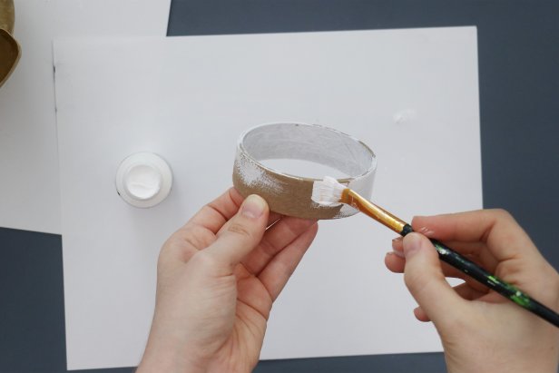 Use an empty masking tape roll for the base. Paint it white and then the same color gold.
