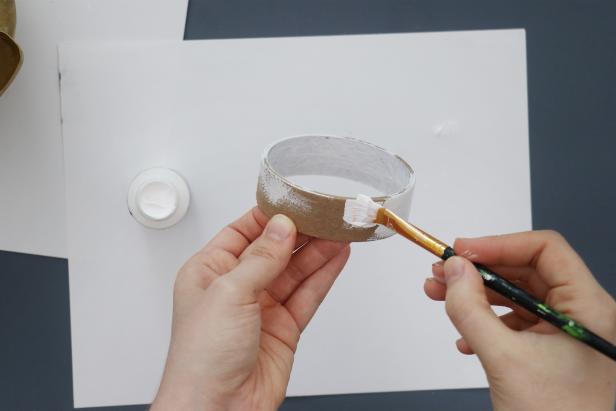 Use an empty masking tape roll for the base. Paint it white and then the same color gold.