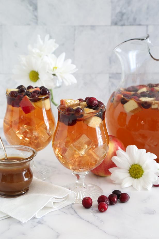 Two Glasses and Pitcher Filled With Caramel Apple Sangria, Cranberries & Apples