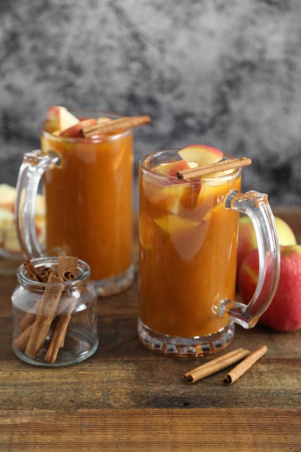 Two Glasses Filled With Pumpkin Spice Apple Cider, Chopped Apples & Cinnamon Sticks